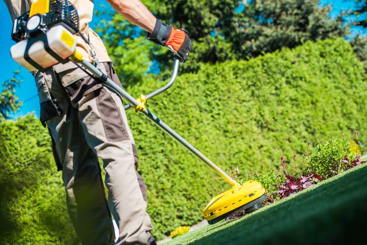 Worker trimming and edging along a garden bed for a clean finish